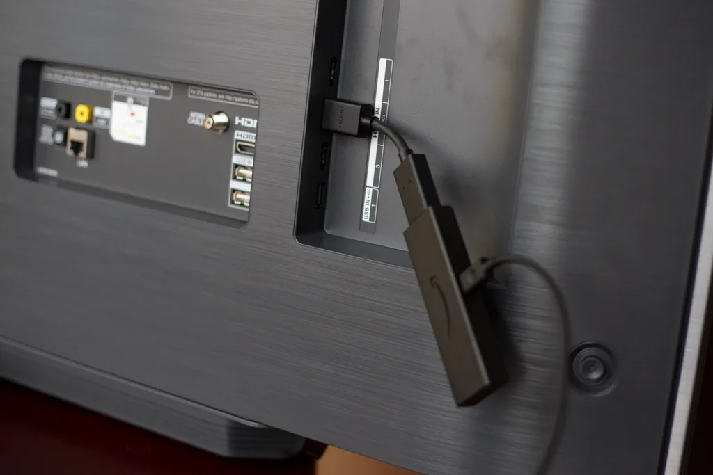 Image of a Fire TV Stick in a Smart TV’s HDMI port, showing the Fire TV interface.