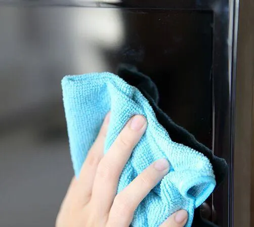 Person cleaning a TV screen using a microfiber cloth