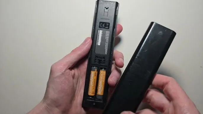 Samsung TV remote with battery compartment open.
